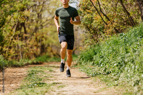 Sport man running. Portrait of runner man jogging in park. Sport workout outdoor. Athlete training run exercise © qunica.com