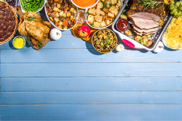 Thanksgiving dinner table with new traditional thanksgiving food - chicken, mashed sweet potatoes, green beans, pecan pie, baked ham pork, mac and cheese, stuffing, modern hard sunny light flatlay