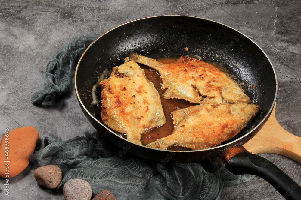 Three fried flounder fish on metal frying pans. Fried fish in a pan Three fried flounder fish on metal frying pans. Fried fish in a pan