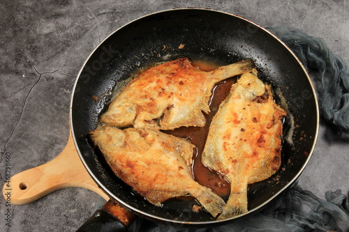 Three fried flounder fish on metal frying pans. Fried fish in a pan 