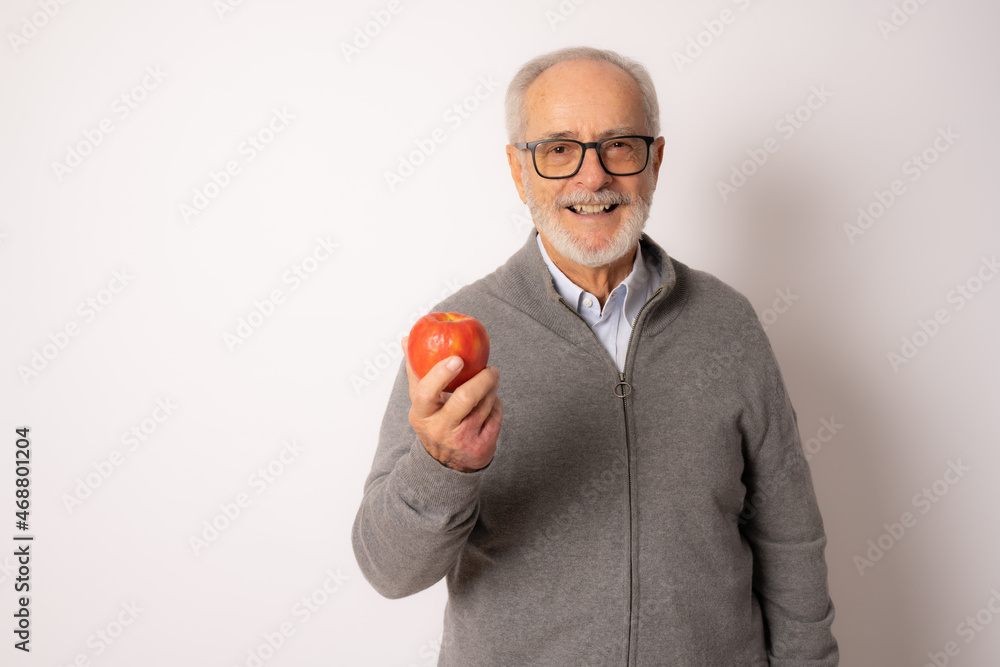 Senior happy man wearing casual sweater eating an apple isolated over white background. Senior happy man wearing casual sweater eating an apple isolated over white background.