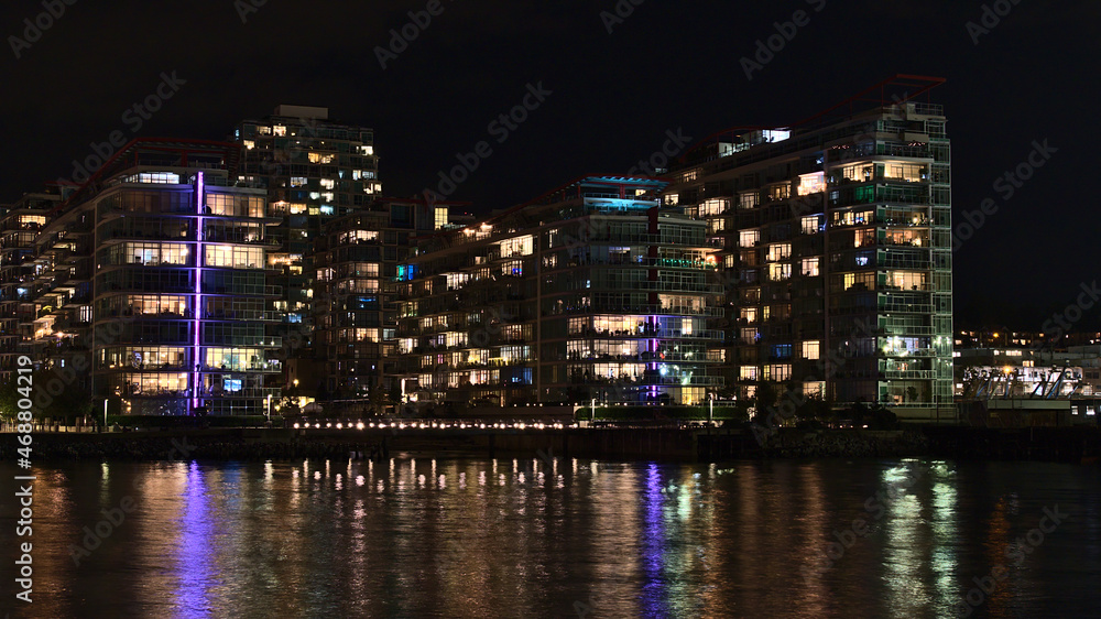 Naklejka premium Beautiful night view of illuminated modern apartment buildings on the shore of Vancouver North, British Columbia, Canada near The Shipyards.
