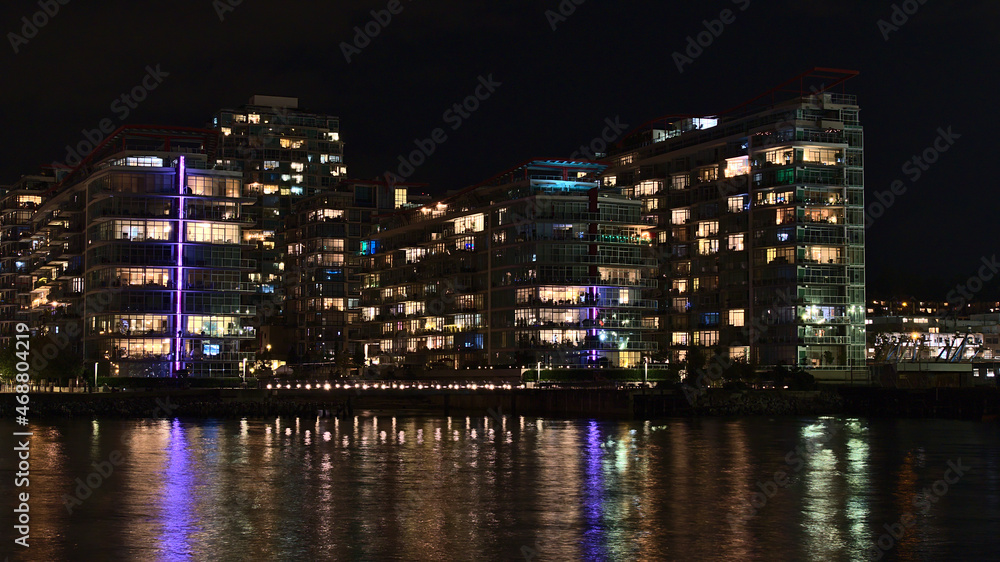 Beautiful night view of illuminated modern apartment buildings on the shore of Vancouver North, British Columbia, Canada near The Shipyards.