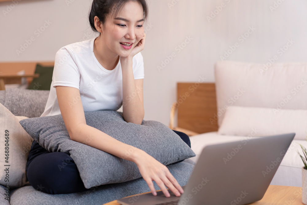Living room concept in the coffee shop a girl with a bun hair using her laptop going on the internet with a glass of orange juice Living room concept in the coffee shop a girl with a bun hair using her laptop going on the internet with a glass of orange juice