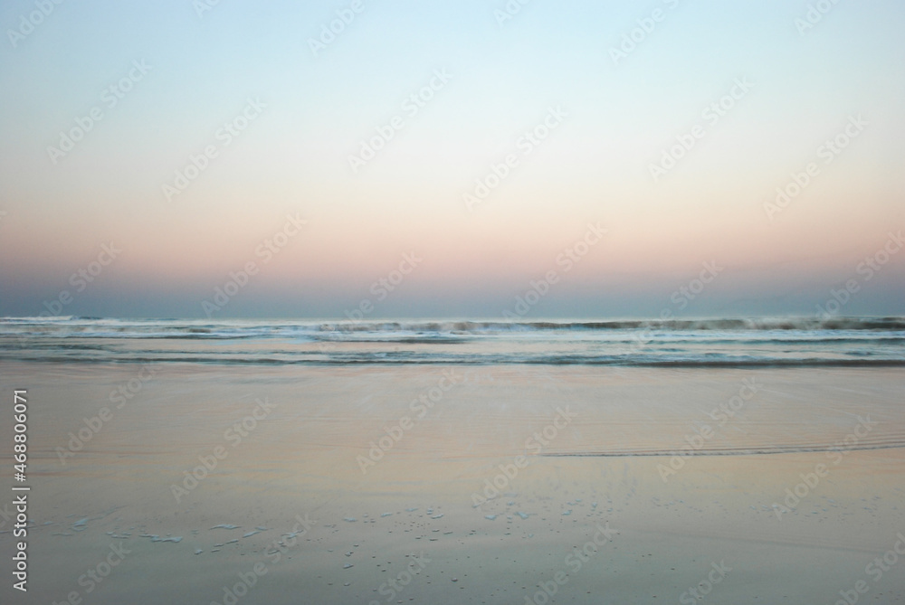 Minimalist moving ocean waves on sandy beach at sunset