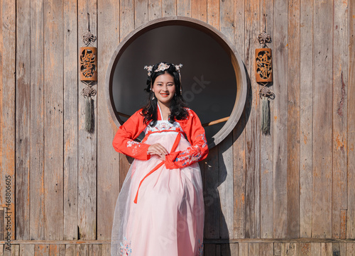 happy Asian woman tourist in red Hanfu ancient Chinese traditional ethnic costume sit in front of wooden window 