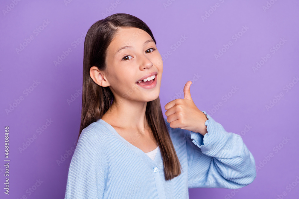 Photo of impressed brunette small girl show thumb up wear blue shirt isolated on violet color background Photo of impressed brunette small girl show thumb up wear blue shirt isolated on violet color background