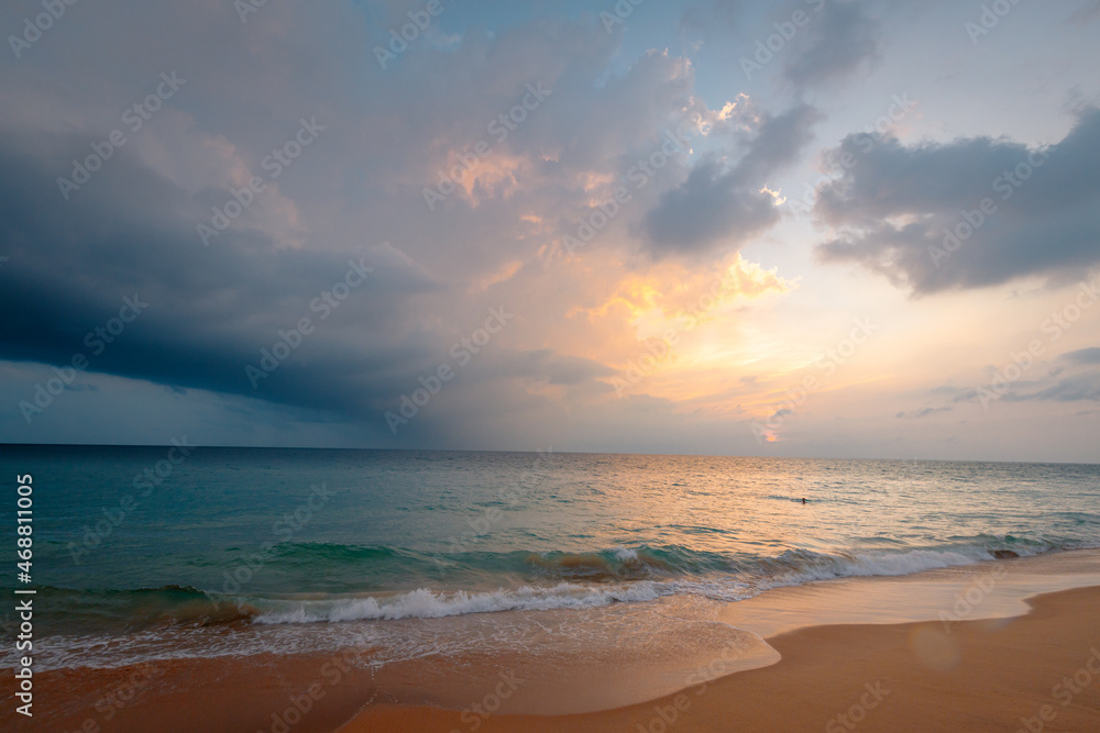 Ocean waves on the sandy beach under a gorgeous sunset sky with clouds on Sri Lanka island.