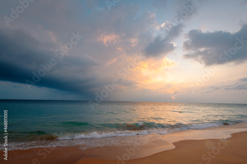 Ocean waves on the sandy beach under a gorgeous sunset sky with clouds on Sri Lanka island.