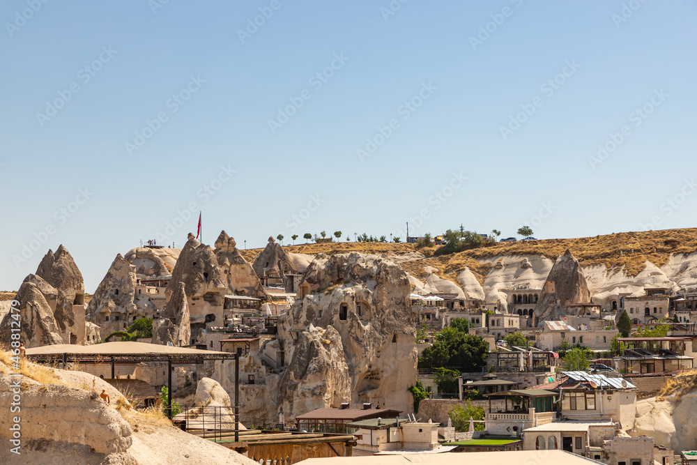 Picturesque of beautiful cave hotels with balcony and cave windows with blue sky during day time. Goreme, Cappadocia, Turkey.