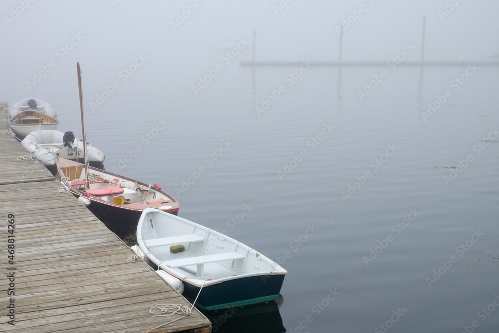 A foggy morning and calm waters with small boats docked on the Maine Coast