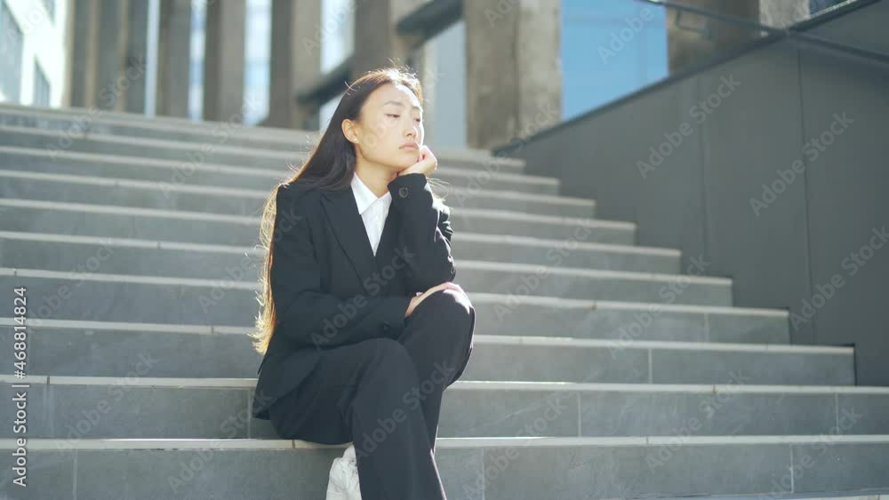 young asian depressed woman sitting on the stairs street near office business center building. Upset female businesswoman lost job due financial crisis and quarantine. student or worker has problem young asian depressed woman sitting on the stairs street near office business center building. Upset female businesswoman lost job due financial crisis and quarantine. student or worker has problem