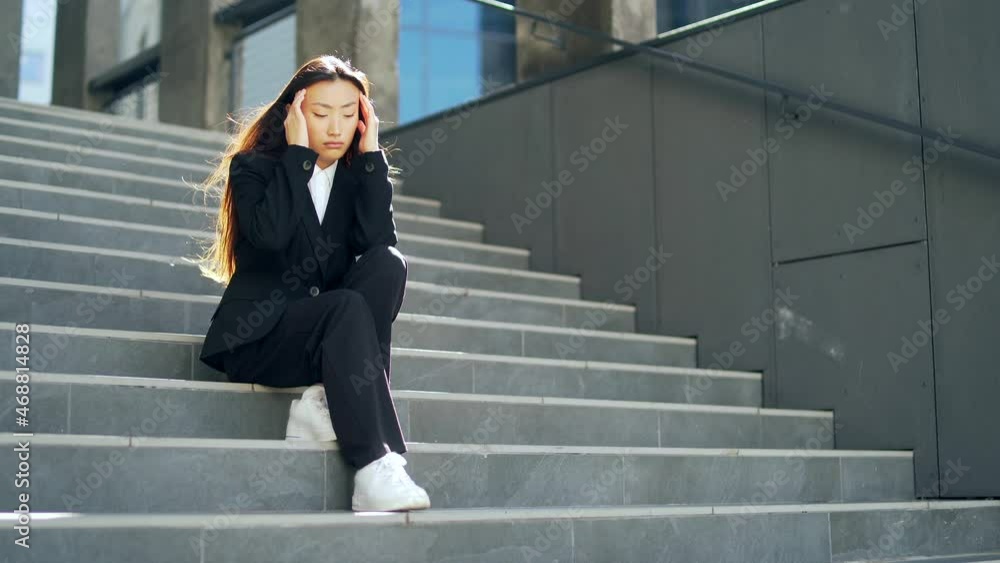 young asian depressed woman sitting on the stairs street near office business center building. Upset female businesswoman lost job due financial crisis and quarantine. student or worker has problem young asian depressed woman sitting on the stairs street near office business center building. Upset female businesswoman lost job due financial crisis and quarantine. student or worker has problem
