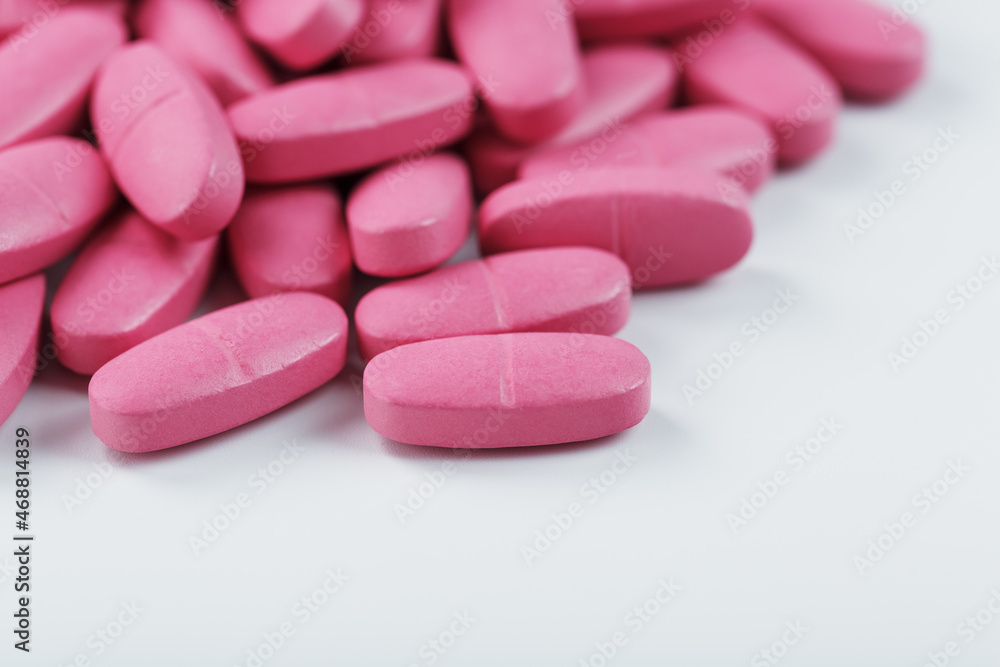 Pink pills with multivitamins on a white background.