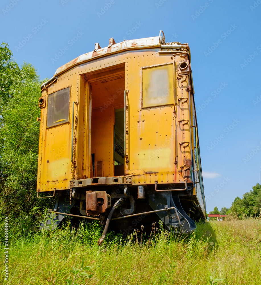 Abandoned yellow passenger car sitting in an old train graveyard