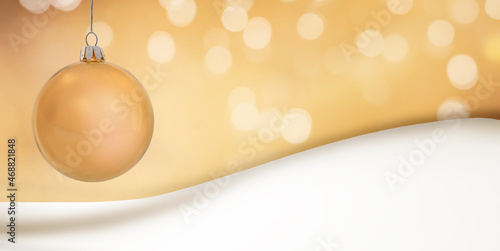 Goldene Weihnachtskugel vor unscharfem Hintergrund und Schneewehe