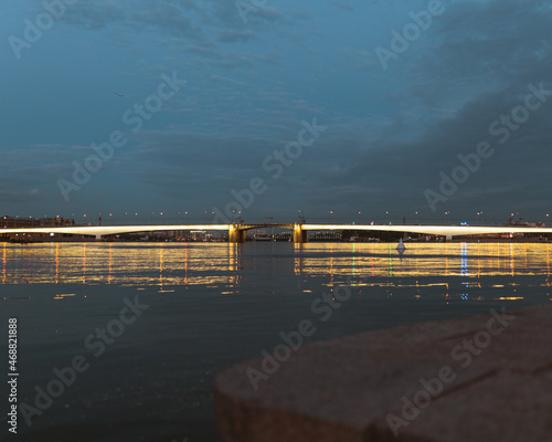 Evening lights of the bridge in the city on the river