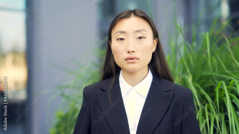 close-up portrait of young attractive asian business woman looking at camera on urban city street background. face of independent confident businesswoman or student. outside. outdoors. Closeup close-up portrait of young attractive asian business woman looking at camera on urban city street background. face of independent confident businesswoman or student. outside. outdoors. Closeup