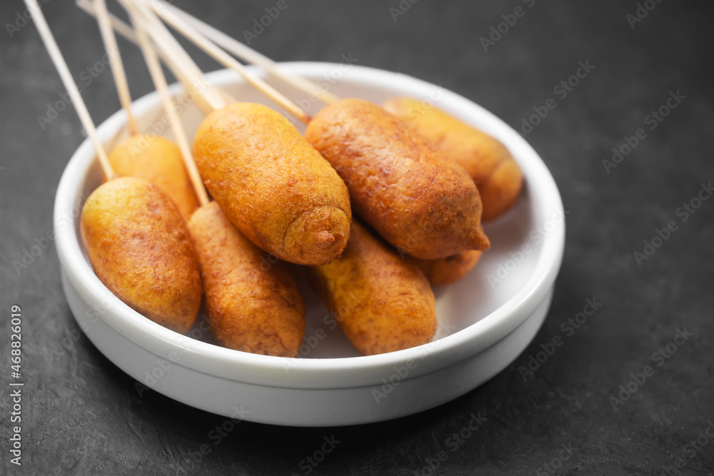 Corn dogs cooked with sausage and dough on a dark background