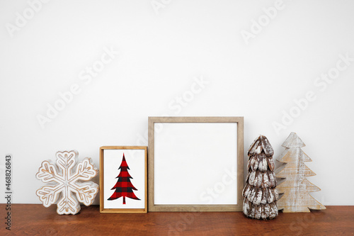 Christmas mock up with wood frame, rustic decor and buffalo plaid sign. Square frame on a wood shelf against a white wall. Copy space. Modern farmhouse concept. photo