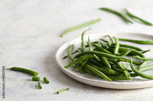 Green beans in a white dish on a white background. 