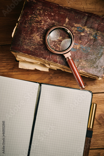 Magnifying glass and the ancient magic book on wooden table