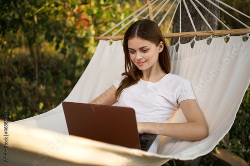 woman lies in a hammock with laptop on nature vacation travel © VICHIZH