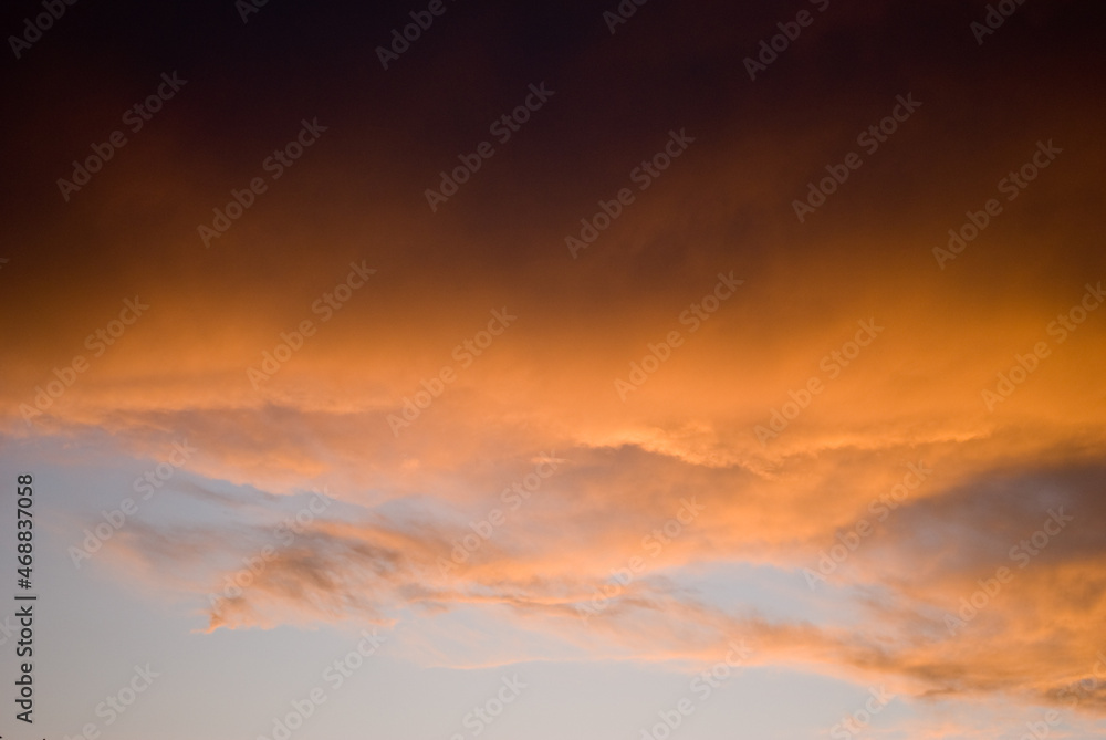 Sunset skies with thunderstorm clouds highlighted with orange hues 