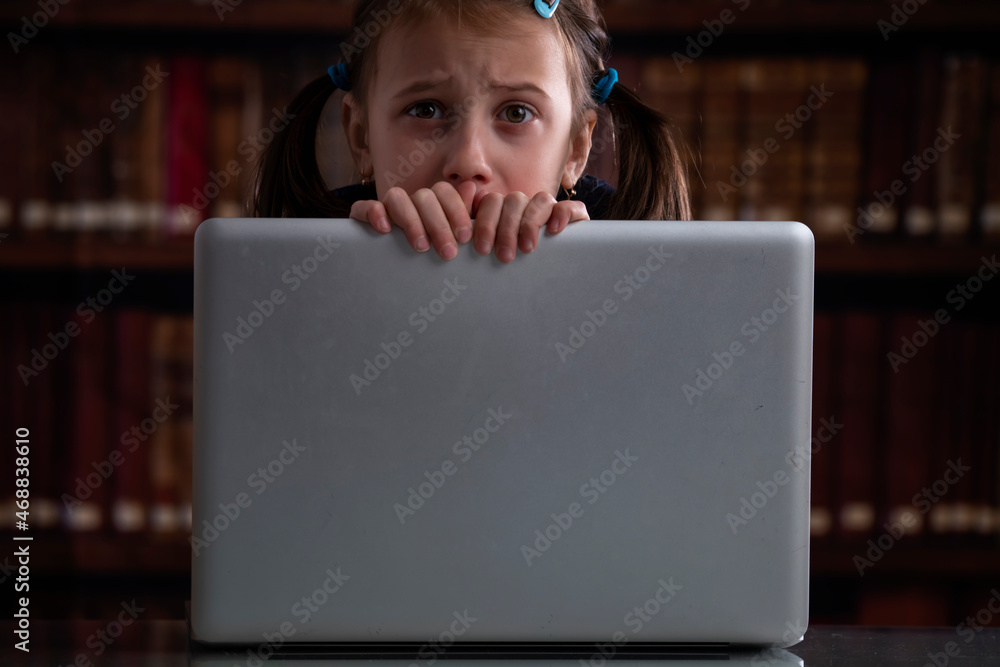 The largest library is a digital library. Young beautiful girl sitting in library and learning with laptop. Copy space. The largest library is a digital library. Young beautiful girl sitting in library and learning with laptop. Copy space.