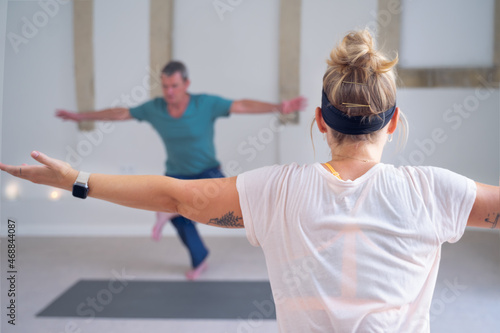 Yoga student, in focus, imitating the pose shown by the instructor.