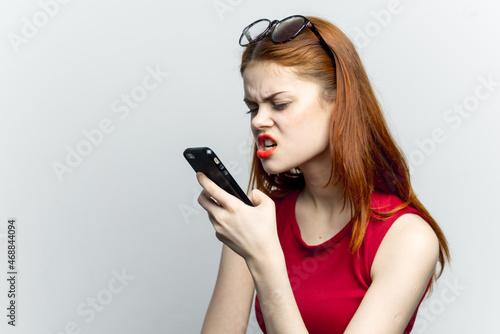 emotional red-haired woman with a phone in her hands communicating gadget