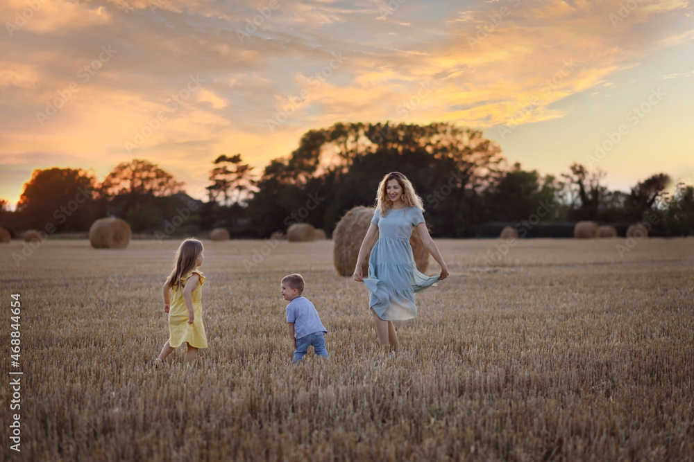 Mother and kids near bales of wheat