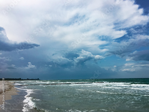 stormy dramatic beautiful clouds over the sea, green water and white sandy beach, copy space