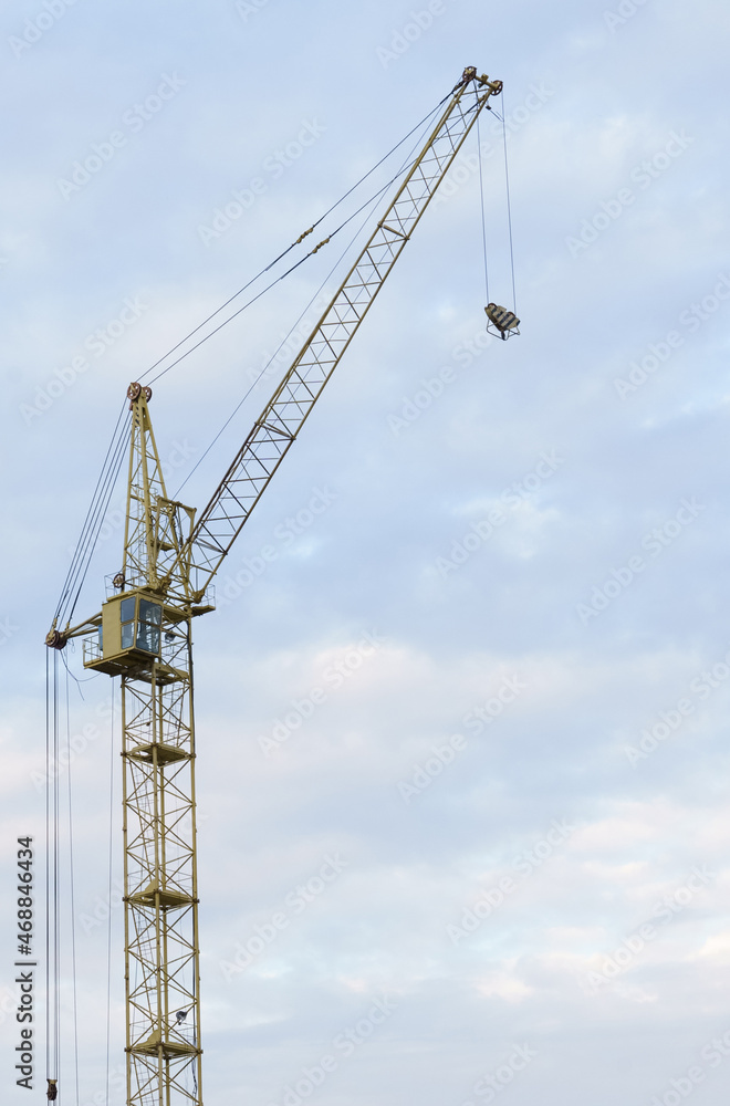 Jib crane on the background of the sky with clouds.