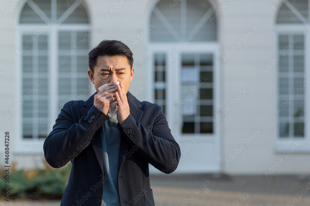 Businessman tired and sick asian man sneezes and coughs on the street, allergic reaction Businessman tired and sick asian man sneezes and coughs on the street, allergic reaction