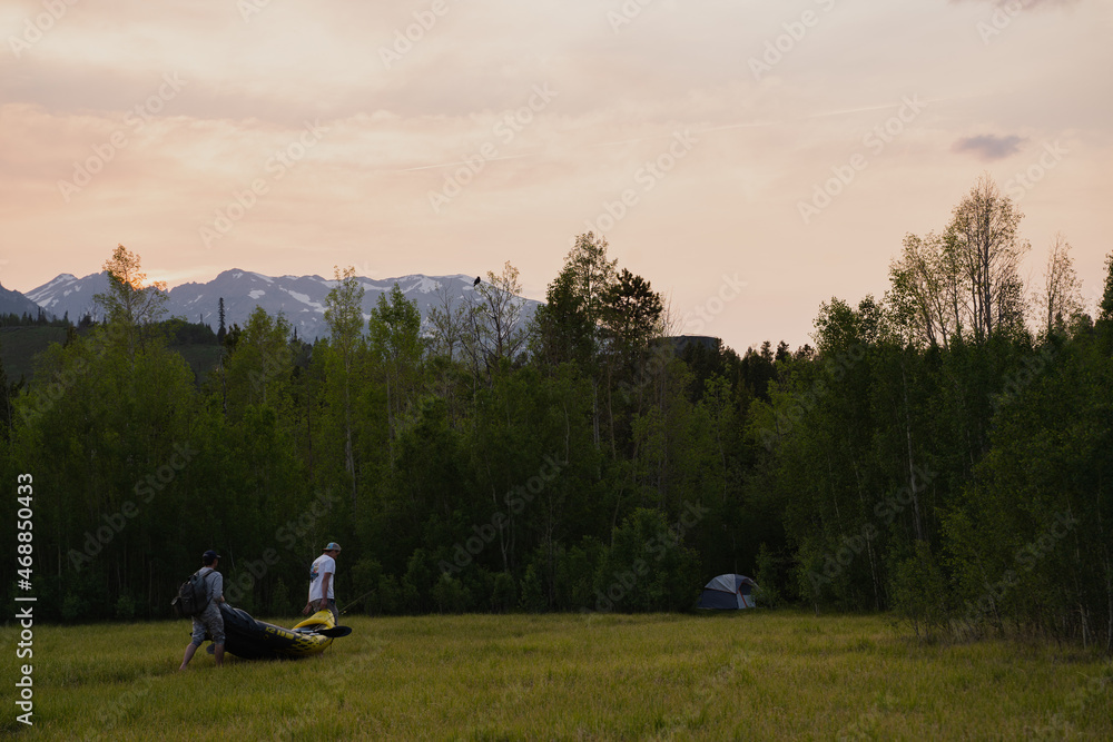 People carrying boat through meadow trees mountain People carrying boat through meadow trees mountain