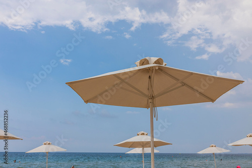 Beautiful view of white sand beach with sun umbrella and sunbed. Greece. © Alex
