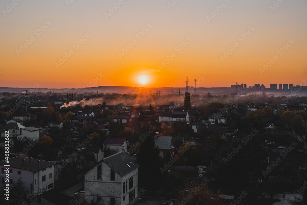 Houses and tall buildings on the horizon in sunset. Place. Scene. Village. View. Lights