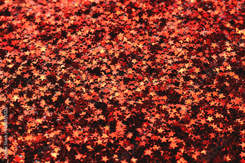A lot of small red shiny stars as a background, festive concept, selective focus