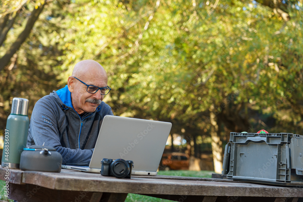 Happy Senior Man Using Computer in Nature