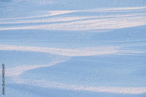 Beautiful winter background with snowy ground. Natural snow texture. Wind sculpted patterns on snow surface.
