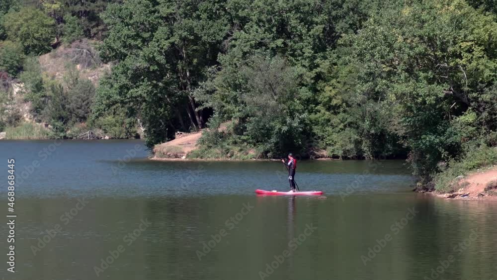 Handsome young man on a paddle board. Getting a great exercise on a lovely river in warm summer day Handsome young man on a paddle board. Getting a great exercise on a lovely river in warm summer day