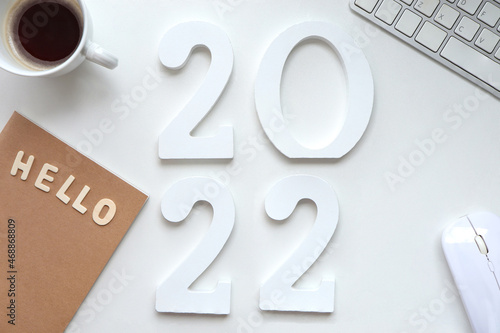 Hello 2022, Wooden number 2022, keyboard and coffee cup on the table. Happy New year 2022 concept. photo