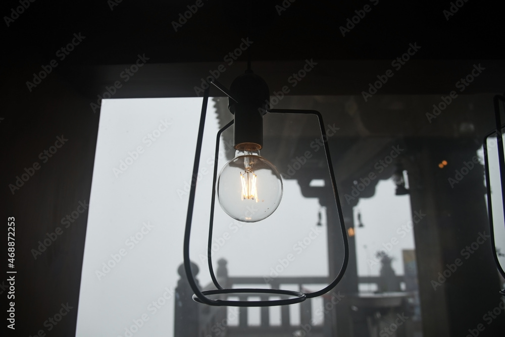 Electric light bulb in a street lamp on the background of architecture elements