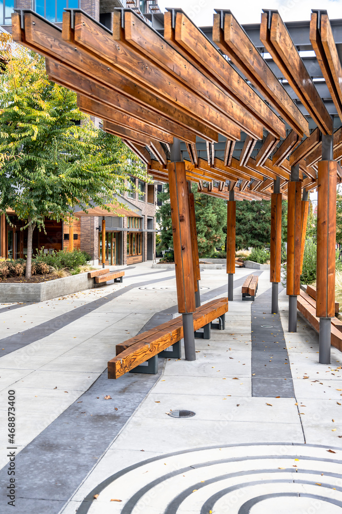 Wooden gazebo with benches near high-rise apartments on the street of an urban city