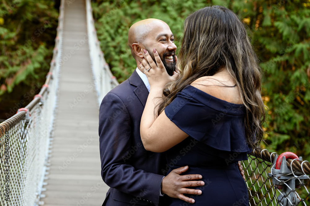 Full of love photo of an affectionate mixed race young couple holding each other on a suspension bridge at sunset Full of love photo of an affectionate mixed race young couple holding each other on a suspension bridge at sunset