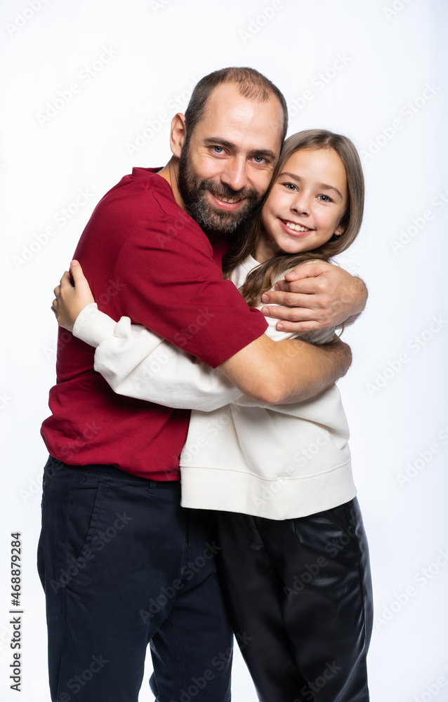 dad hugs daughter by the shoulders in the studio. a man in a burgundy-red T-shirt, a girl in a white sweatshirt. isolated white background dad hugs daughter by the shoulders in the studio. a man in a burgundy-red T-shirt, a girl in a white sweatshirt. isolated white background