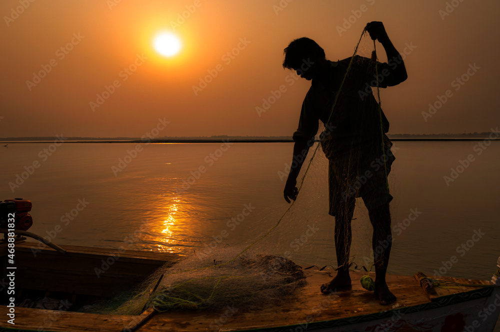 beautiful silhouette pictures  with boat and fisherman with net during sunset in golden light 