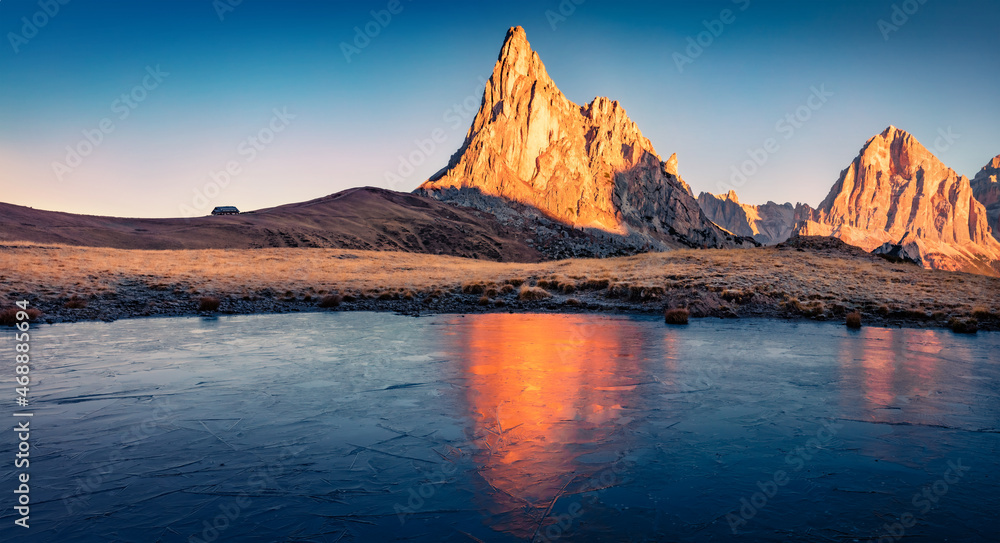 Frozen small lake at the foot of Ra Gusela mountain. Fantastic sunrise in Dolomite Alps. Cologrull morning scene of Giau pass, Italy, Europe. Beauty of nature concept background..