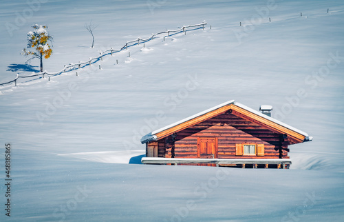 Lonely wooden chalet on the snowy hill. Bright morning view of Alpe di Siusi village. Stunning winter scene of Dolomite Alps, Ityaly, Europe. Traveling concept background.. photo